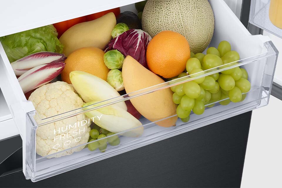 Szczegółowy widok na wnętrze specjalnej szuflady Humidity Fresh+. Znajdują się w niej owoce takie jak winogrona czy pomarańcza, a także warzywa takie jak kalafior i brukselki.