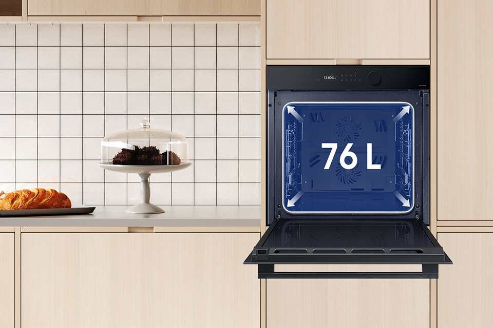 Zdjęcie przedstawia dostępny w sklepach Media Expert piekarnik Samsung NV7B5660RAK umieszczony w jasnej zabudowie kuchennej oraz informację o pojemności komory wynoszącej 76 litrów